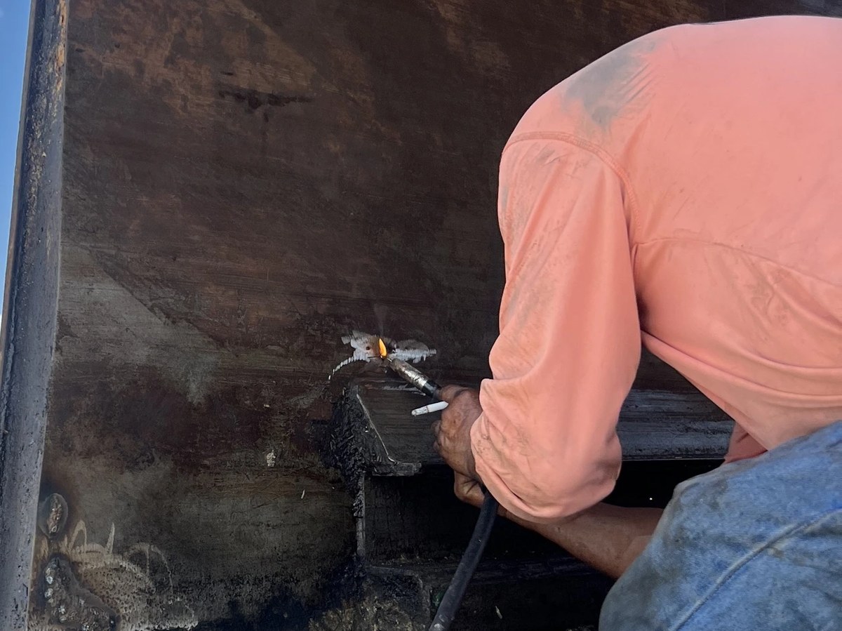 KZ technician welding a structural repair on the interior body of a front-load garbage truck — Lakeland, Florida